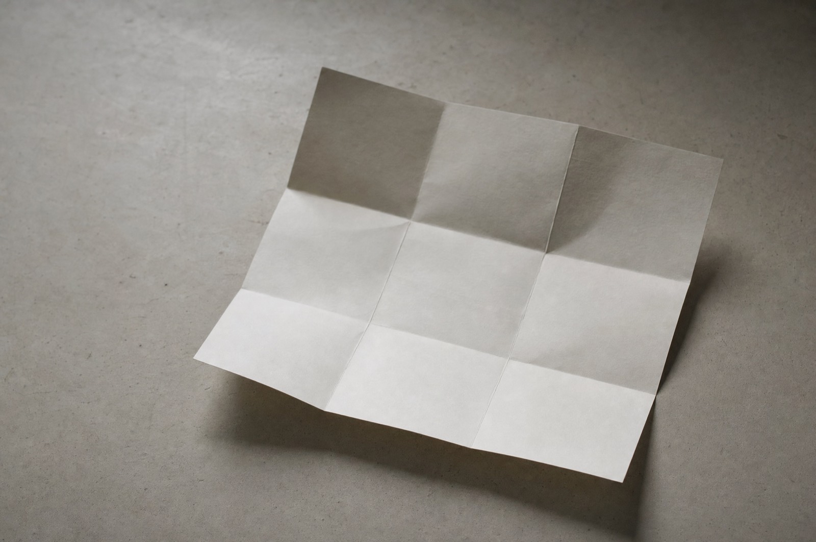 A sheet of heavy off-white paper folded into a shallow grid of creases