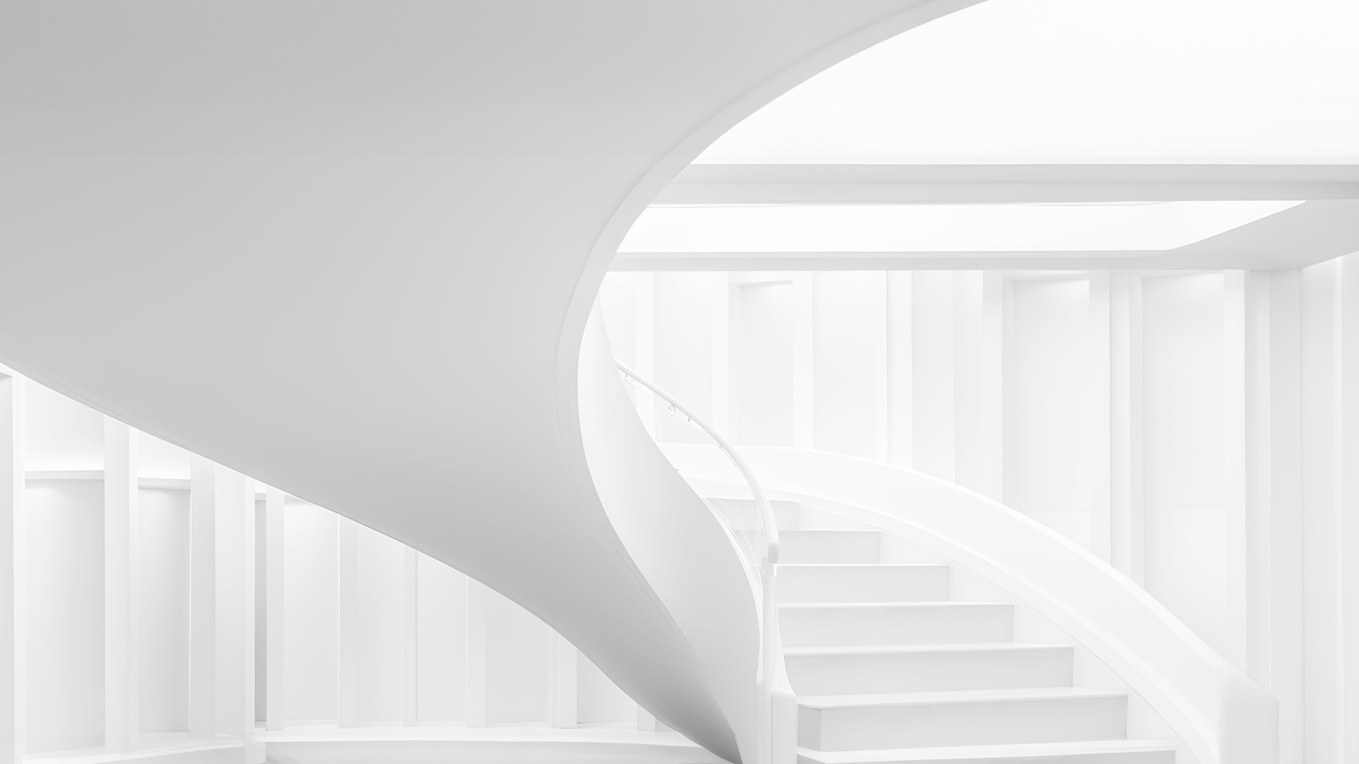 A white spiral staircase curving through a bright, empty room