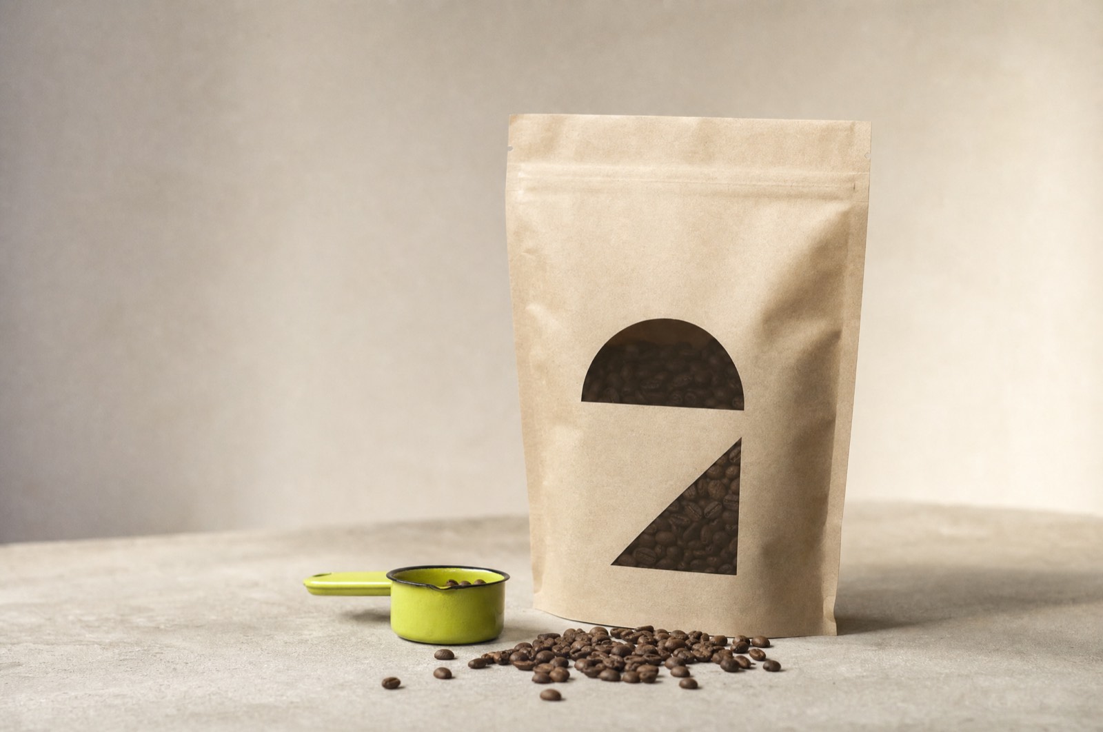 A kraft coffee bag with a die-cut geometric mark beside scattered beans