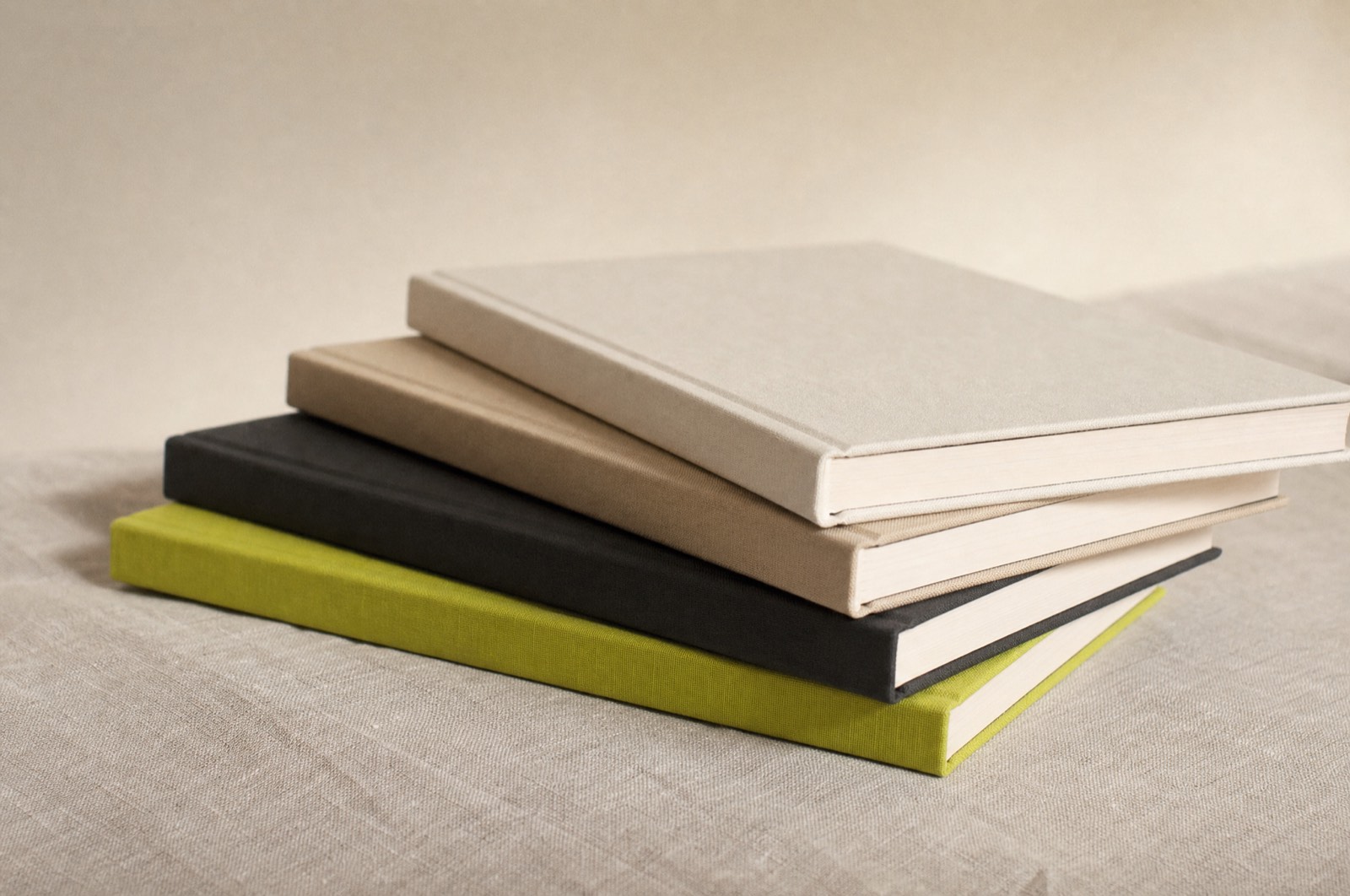 Four slim hardback books with plain uncoated covers, one spine in lime