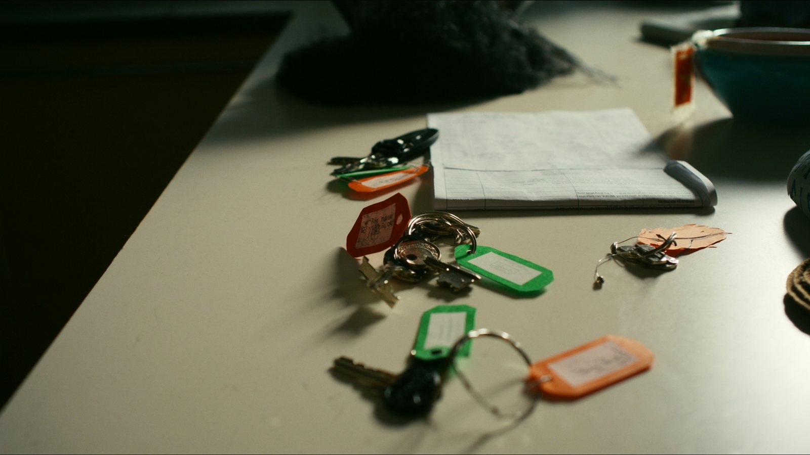 House keys with colourful tags on a kitchen table beside a lease