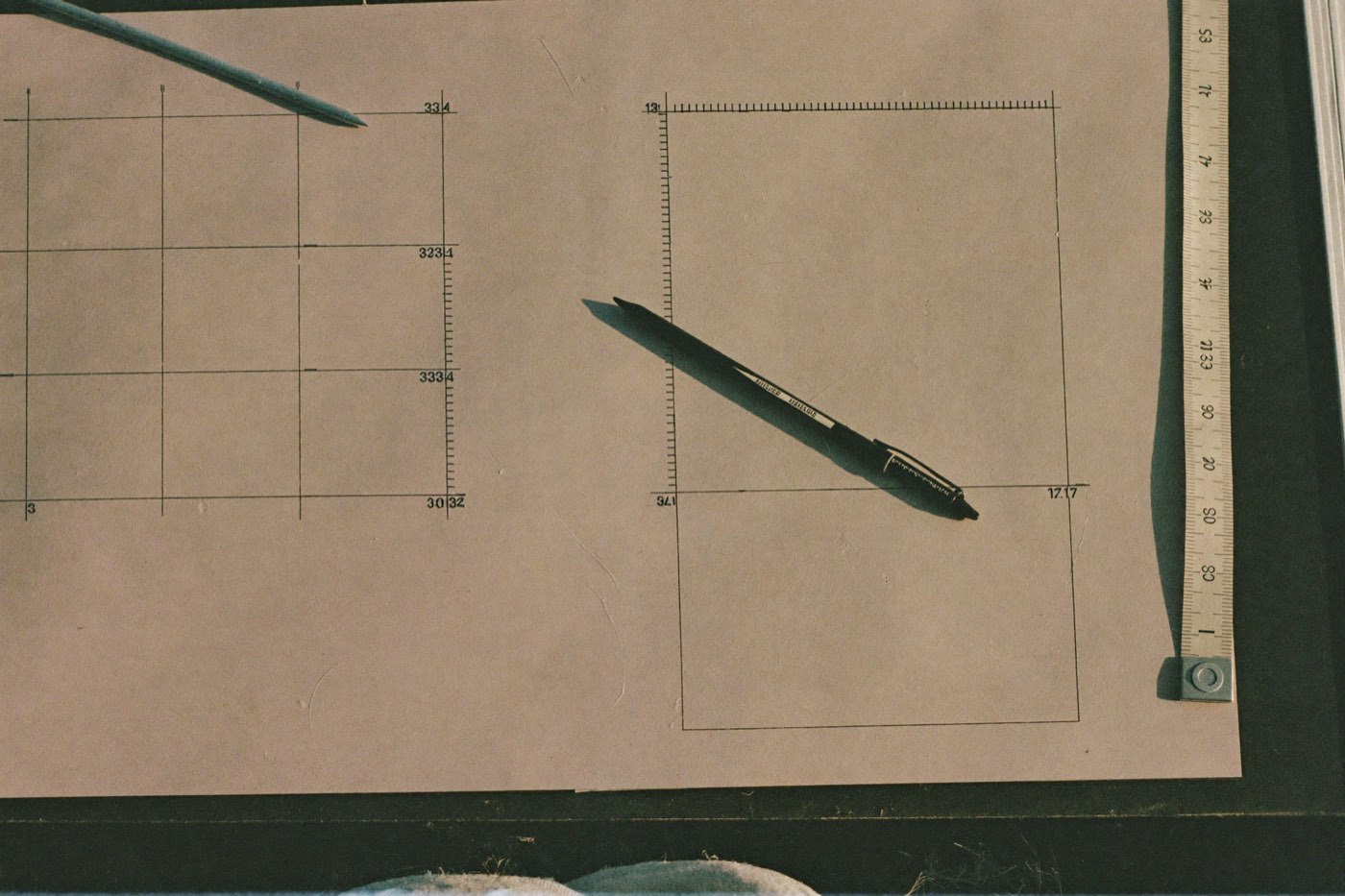 A printed wireframe grid on bone paper with a black fineliner across it