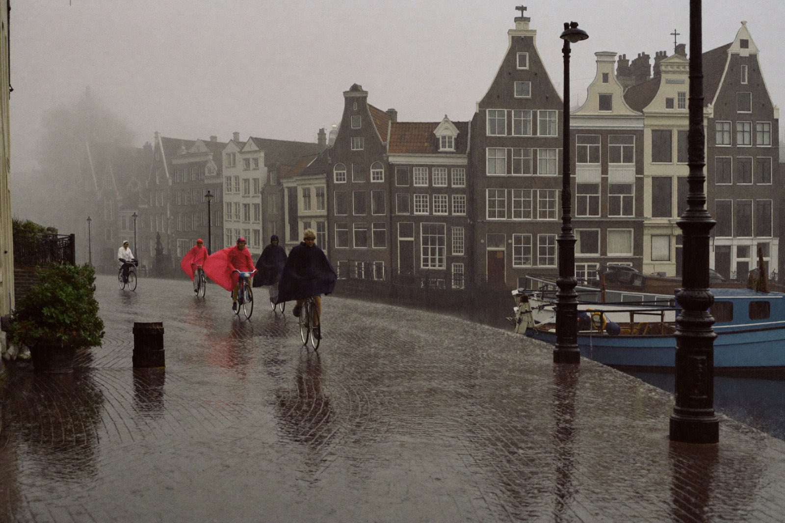 Cyclists crossing a canal bridge in steady rain