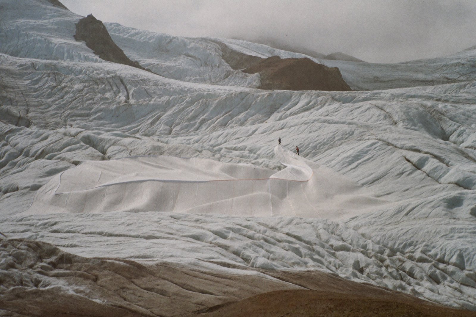 An alpine glacier partly covered in white protective blankets