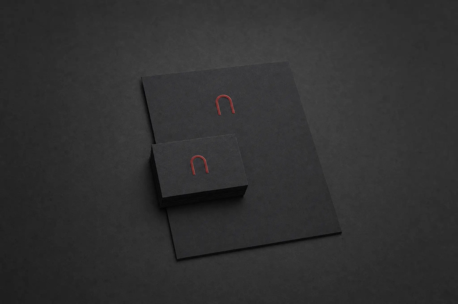 Aura brand identity — the red arch mark embossed on black stationery